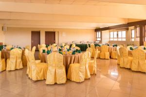 ThikaEton Hotel的宴会厅配有桌椅和黄饰