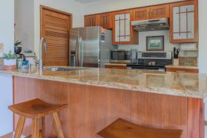 瓦克拉Shores at Waikoloa #108的厨房配有花岗岩台面和木制橱柜