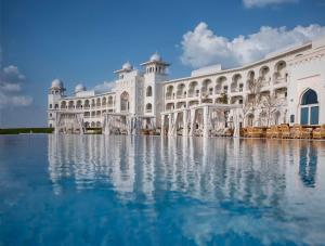 多哈The Chedi Katara Hotel & Resort的一座白色的大建筑,前面有水
