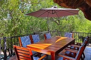 玛洛斯帕克Kruger Park Hostel的甲板上配有一张木桌和椅子及遮阳伞