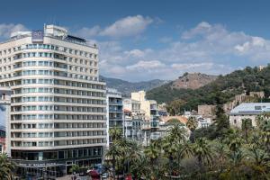 马拉加AC Hotel Málaga Palacio by Marriott的一座高大的白色建筑,位于一个棕榈树城市