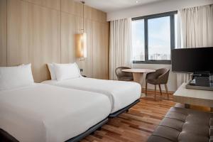 马拉加AC Hotel Málaga Palacio by Marriott的酒店客房设有两张床和一张桌子。