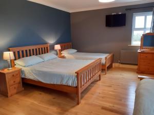 康镇Whitethorn Lodge, Bed & Breakfast, Lackafinna的一间卧室设有两张床,墙上配有电视。