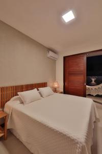 佩德拉斯港Pousada Praia do Patacho的卧室配有一张白色大床和电视。