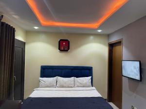拉各斯Suite Subzero的一间卧室配有一张带蓝色床头板的床和一台电视。