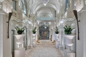布达佩斯Matild Palace, a Luxury Collection Hotel的建筑中带有白色柱子和植物的走廊