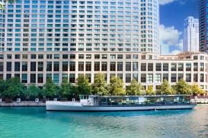芝加哥Sheraton Grand Chicago Riverwalk的大型建筑前的水面上的船