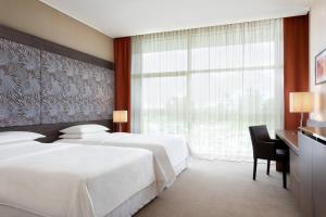 Ferno喜来登米兰马尔彭萨机场酒店及会议中心的酒店客房设有两张床、一张书桌和一个窗户。