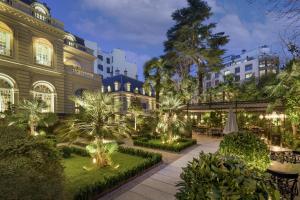 马德里Santo Mauro, a Luxury Collection Hotel, Madrid的一座有树木和灯光的建筑的庭院