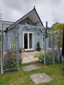 HoldenhurstPrivate Garden Lodge in Christchurch, Dorset for 4 - dogs welcome!的一座蓝色的小房子,前面有一个门