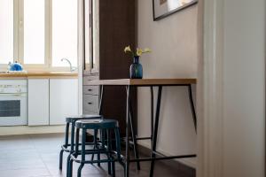 罗马泰尔米尼公寓的厨房配有一张桌子和两张蓝色凳子