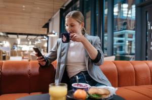 埃斯波Heymo 1 by Sokos Hotels的坐在桌子旁拿着手机的女人