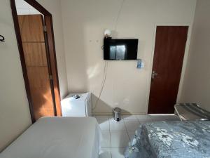 费尔南多 - 迪诺罗尼亚Casa do Anjo的小房间设有一张床和墙上的电视