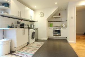 伦敦绝美伊斯特芬奇利公寓的厨房配有白色橱柜、洗衣机和烘干机