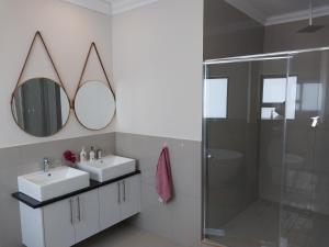 布鲁堡史特兰LND GUEST HOUSE的一间带两个盥洗盆、淋浴和镜子的浴室