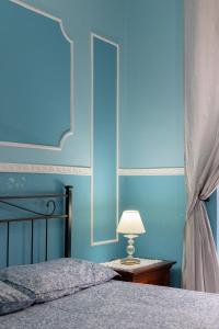 那不勒斯SpaccaNapoli Home的一间拥有蓝色墙壁的卧室和一张带灯的床