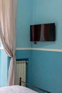 那不勒斯SpaccaNapoli Home的一间卧室设有蓝墙、窗帘和电视