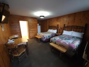 沃瓦Outdoorsman Motel的一间卧室配有两张床、一张桌子和一张桌子