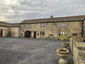StanningleyThe Farm House Modern spacious 2 bedroom home at Tong road Leeds perfect for contractors free secure parking的一座古老的砖房,前面有植物