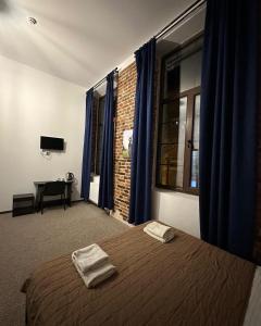 利沃夫Hotel Rover的一间卧室配有一张带蓝色窗帘的床和一张书桌