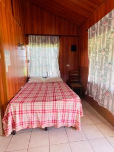 奥兰治沃克Lamanai Riverside Retreat的一间卧室配有一张带红白格子毯子的床