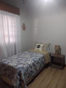 罗卡将军市Casa pura vida的卧室配有一张床,窗户旁设有床头柜