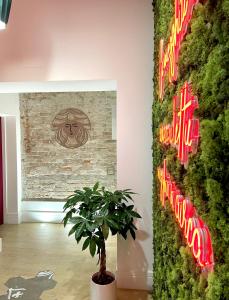 雷焦卡拉布里亚XENIA LUXURY ROOMS的 ⁇ 虹灯标志的墙上的植物