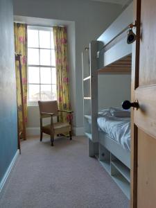 伊尔弗勒科姆朗时登大厦的一间卧室配有双层床、椅子和窗户。
