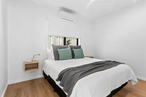 林肯港Port Lincoln Beachfront Apartments的白色卧室配有一张带绿色枕头的大床
