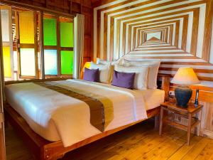 皮皮岛披披岛小木屋度假酒店的一间卧室配有一张带紫色枕头的大床