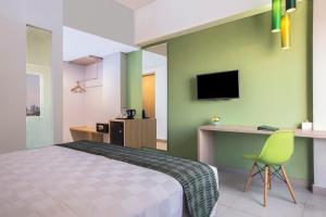 马卡萨KHAS Makassar Hotel的一间卧室配有一张床、一张书桌和一台电视。