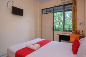 美娜多RedDoorz @ Jalan Pramuka Manado的一间卧室设有两张床、一张桌子和一个窗口。