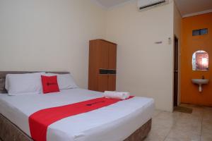 美娜多RedDoorz near Jalan Wolter Monginsidi Manado的一间卧室配有一张床铺,床上铺有红色毯子