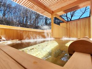轻井泽小濑温泉酒店的一个带瀑布的木屋内的热水浴池