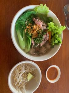 Phumĭ Chŏng KaôhHeangKanha GuestHouse的木桌上放两碗食物