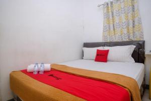 PanikiRedDoorz near Politeknik Manado的一间卧室配有一张床铺,床上铺有红色毯子