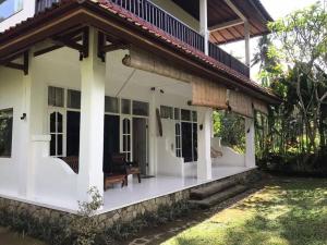 乌布Villa Kassi: 1 bed en-suite, large garden, pool.的白色的房子,带长凳的门廊