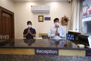 哈里瓦Perfect Stayz Dwarkesh - Hotel Near Haridwar Railway station的两个戴面具的男子在柜台祈祷