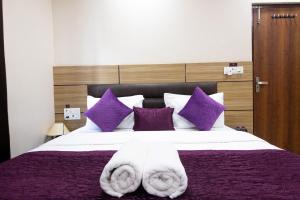 哈里瓦Perfect Stayz Dwarkesh - Hotel Near Haridwar Railway station的一间卧室配有一张大床,提供紫色和白色枕头