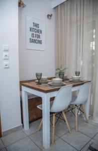 塞萨洛尼基Fobillo Apartment at Charilaou的餐桌、白色椅子和墙上的照片