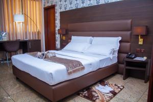 雅温得New Heaven Hôtel的一间卧室配有一张大床和棕色床头板