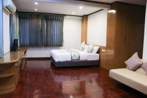暖武里府Bed By Cruise Hotel At Samakkhi-Tivanont的一间卧室配有一张床、一台电视和一张沙发