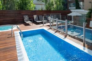巴塞罗那加泰罗尼亚米卡多酒店的一个带椅子和桌子的游泳池以及一把遮阳伞