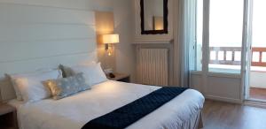 昂代乌哈纳克酒店的一间卧室配有带白色床单和枕头的床。