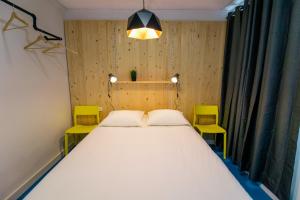 阿利坎特Koala Hostel的卧室配有一张白色大床和两张黄色椅子