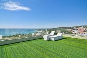 瓦尔纳Sea lounge的绿色草坪上的阳台配有两把白色椅子