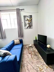 约翰内斯堡Cosy Apartment next to Maboneng的客厅配有蓝色的沙发和电视