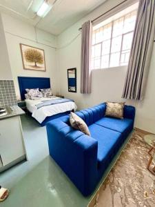 约翰内斯堡Cosy Apartment next to Maboneng的客厅配有蓝色的沙发和床。