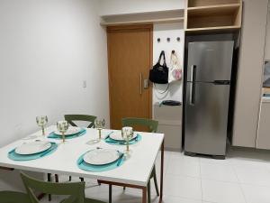 嘎林海斯港Mana Beach Experience - Muro Alto - Flat Luxo 2 qtos的厨房配有白色桌椅和冰箱。