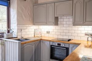 Castle CarrockMill Barn, Castle Carrock, Nr Carlisle的厨房配有白色橱柜、水槽和烤箱。